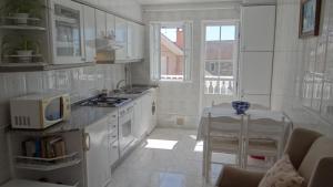 a kitchen with white cabinets and a table with a microwave at Casa Bruna 1º A Apartamento a 800 m de la playa in Lariño