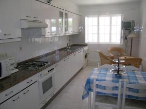a kitchen with white cabinets and a table with a blue and white table at Casa Bruna Baixo A Apartamento a 800 m de la playa in Lariño