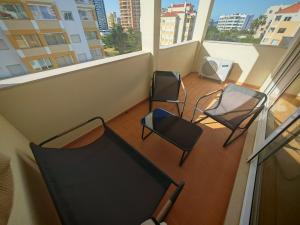 three chairs and a table on a balcony with windows at Buzios Praia da Rocha in Portimão