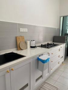 a white kitchen with a stove and a sink at De' Haven Stay - 10minutes to Airport Tawau in Tawau +8 photos