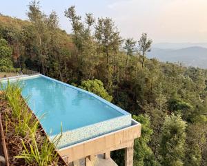 a swimming pool in the middle of a forest at kollanoor guest house in Madikeri