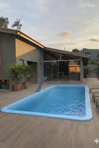 a large blue swimming pool on a deck with a house at Villa di kona in Serra Negra