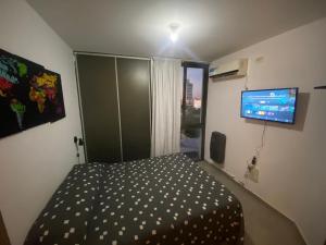 a bedroom with a bed and a flat screen tv at Dpto en la costa in Villa María