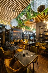 ein Restaurant mit Tischen, Stühlen und Kronleuchtern in der Unterkunft Hotel Allora in Budapest