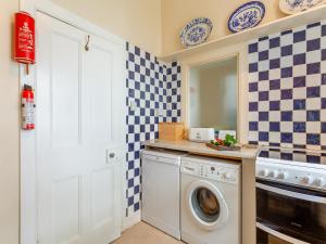 a laundry room with a washing machine and blue and white tiles at The Ivy Wing in Slickly +15 photos