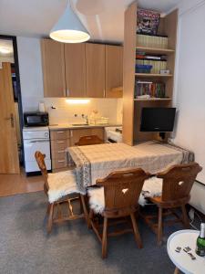 a kitchen with a table and some chairs and a table and a television at Rogla Gaber Studio in Zreče