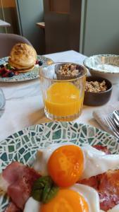 a table with a plate of breakfast food and a glass of orange juice at Casa Zogbi Hotel in Porto