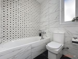 a white bathroom with a toilet and a bath tub at Stylish Seaview Retreat in St Pauls Bay in St. Paul's Bay +15 photos