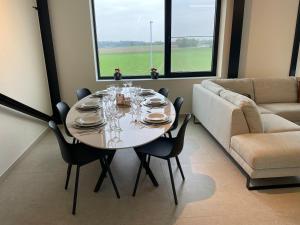 a dining room with a table and a couch at Klein Vloethemnest in Zedelgem