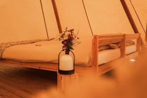 a vase of flowers sitting on a table next to a bed at Förland Sunnemo in Sunnemo