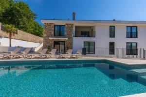 a house with a swimming pool with chairs and a building at Villa Jackie in Bribir