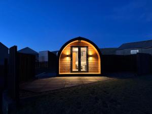 a small house with a wooden door at night at Millfield Glamping Pods - Heatherhouse in Orkney