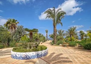 a park with two benches and palm trees at Occidental Mar Menor in Cartagena +127 photos