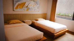 a bedroom with two beds and a window at Miracle Hotel Cianjur in Pasirhayam