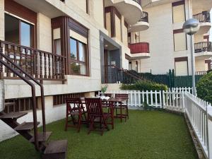 a patio with chairs and a table in front of a building at Apartamento en la playa con piscina - Azcona 6004 in Noja