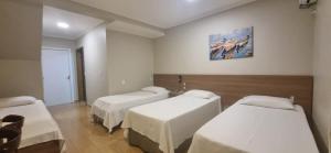 a room with three beds and a painting on the wall at Pousada Recanto do Mar in Navegantes