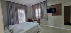 a bedroom with a bed and a flat screen tv at Pousada Recanto do Mar in Navegantes