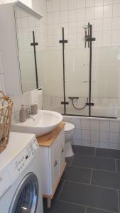 a white bathroom with a sink and a washing machine at Ferienwohnung Stadtblick Königstein in Königstein an der Elbe