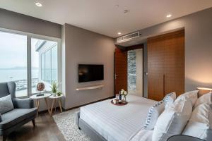a bedroom with a bed and a couch and a tv at White Sands Beachfront l 2BR Condo with Ocean View in Na Jomtien