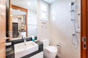 a bathroom with a sink and a toilet and a mirror at White Sands Beachfront l 2BR Condo with Ocean View in Na Jomtien +20 photos