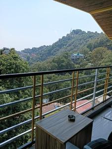 a balcony with a table and a view of a mountain at The Hostelers Homestay Shimla - Near ISBT, Bypass MC Parking and HPU in Shimla