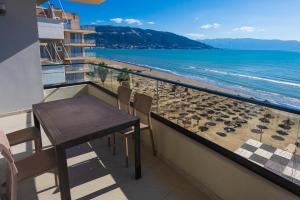 a balcony with a table and chairs and the beach at IDeal Sea View Apartment in Vlorë