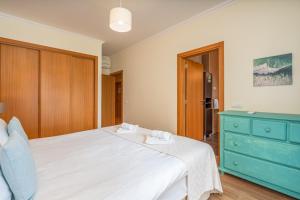 a bedroom with a white bed and a blue dresser at #010 Marina View Apartment Pool & Balcony in Albufeira