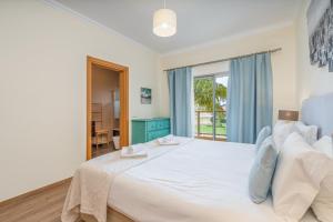 a bedroom with a large white bed and a window at #010 Marina View Apartment Pool & Balcony in Albufeira