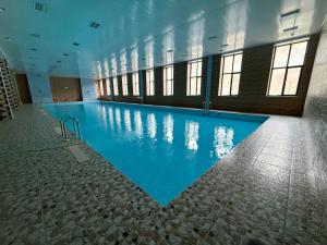 a large swimming pool with blue water in a building at Imperial Hotel in Kapan