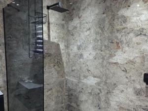 a bathroom with a shower with a stone wall at Bush Diamond Lodge in Cullinan +8 photos