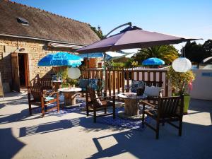 a patio with tables and chairs with umbrellas at Camping Kerscolper - Mobil home 3 pièces 4/6 personnes + TV MAE-9591 in Fouesnant