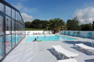 a swimming pool with chairs and people in it at Camping Kerscolper - Mobil home 3 pièces 4/6 personnes + TV MAE-9591 in Fouesnant