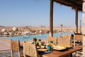 a table with food on it next to a swimming pool at Agafay Valley in Marrakesh +66 photos