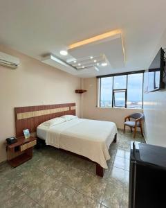 ein Schlafzimmer mit einem Bett, einem Tisch und einigen Fenstern in der Unterkunft Hotel Torre Azul in Santo Domingo de los Colorados