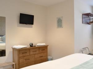 a bedroom with a bed and a tv on the wall at Park View Cottage in Stranraer