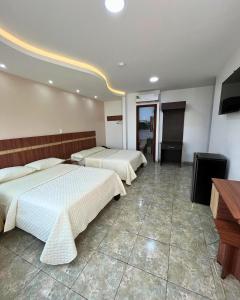 ein Hotelzimmer mit zwei Betten und einem Fernseher in der Unterkunft Hotel Torre Azul in Santo Domingo de los Colorados + 19 Fotos