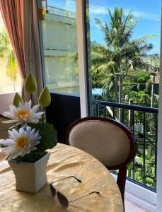 a table and a chair and a vase with flowers at BOUTIQUE-VILLA with Suites & Rooms in Karon Beach