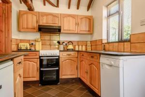 a kitchen with wooden cabinets and white appliances at 1 Bed in Saxmundham oc-c27420 in Farnham