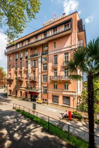 ein großes orangefarbenes Gebäude mit einer Palme davor in der Unterkunft Hotel Federale in Lugano