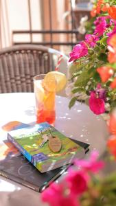 Ein Buch und ein Getränk auf einem mit Blumen geschmückten Tisch in der Unterkunft Hotel Federale in Lugano