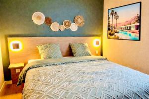 a bedroom with a large bed and some lights at Appartement cosy ambiance Palm Spring dans résidence avec piscine 4 pers 2 chambres in Neuf-Mesnil +19 photos