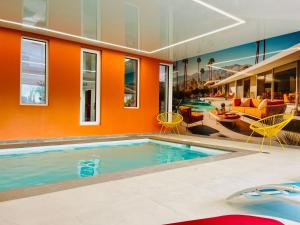 an indoor pool in a house with orange walls at Appartement cosy ambiance Palm Spring dans résidence avec piscine 4 pers 2 chambres in Neuf-Mesnil