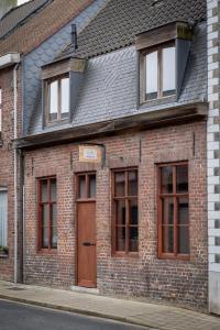 a brick building with a brown door and windows at In De Rooden Hoed in Poperinge