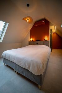 a bedroom with a large white bed with a red wall at In De Rooden Hoed in Poperinge +98 photos