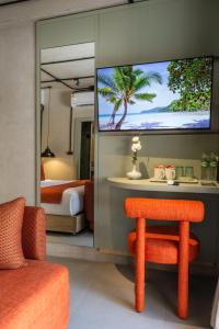 a room with a bedroom with a tv and a chair at Aloha Tropicana Samui in Chaweng