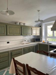 a kitchen with green cabinets and a table with chairs at Casa Mariannina in Maiori