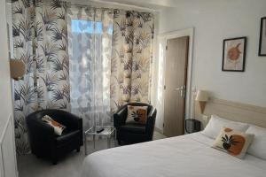 a hotel room with two chairs and a bed at Vieille tour Hotel centre Rouen in Rouen