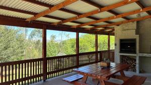 a screened in porch with a wooden table and a fireplace at The Stix in Dullstroom