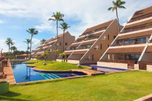 a row of apartment buildings with palm trees in the background at Cumbuco Ocean View in Cumbuco