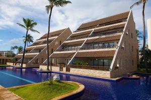 a building with a swimming pool and palm trees at Cumbuco Ocean View in Cumbuco +17 photos